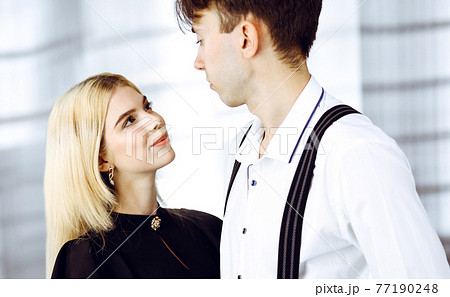 Young couple of businessman and woman are standing in a modern office. Portrait of successful business people 77190248