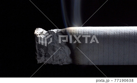 Photo of smoldering cigarette with filter on black 77190638
