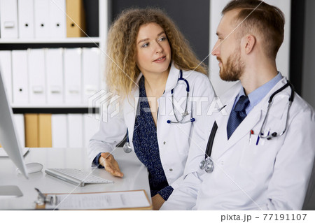 Male doctor withcolleague discussing current disease therapy while sitting at working place in clinic. Team work in medicine Male doctor withcolleague discussing current disease therapy while sitting at working place in clinic. Team work in medicine 77191107