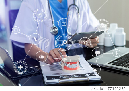 Concentrated dentist sitting at table with jaw samples tooth model and working Concentrated dentist sitting at table with jaw samples tooth model and working 77191223