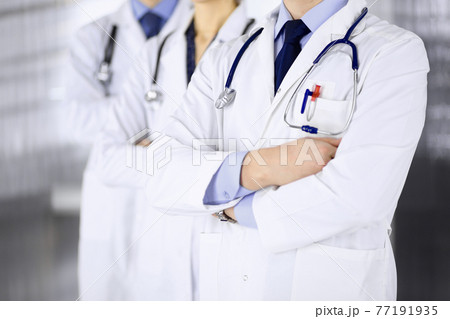 Group of modern doctors standing as a team with crossed arms and stethoscopes in hospital office. Physicians ready to examine and help patients. Medical help, insurance in health care, best desease 77191935