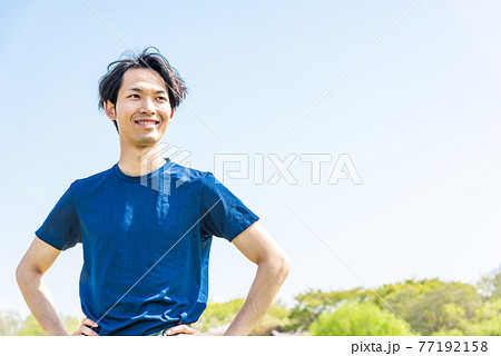 公園でランニング前にストレッチをする若い男性 77192158