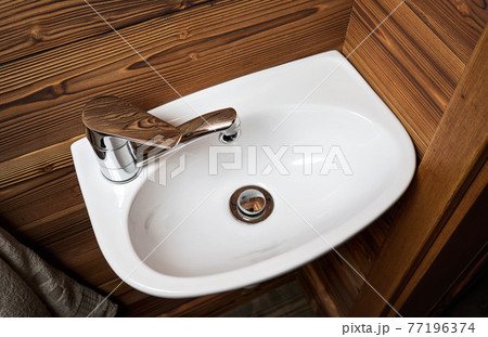 Small white wash basin, wooden walls around, closeup detail Small white wash basin, wooden walls around, closeup detail 77196374