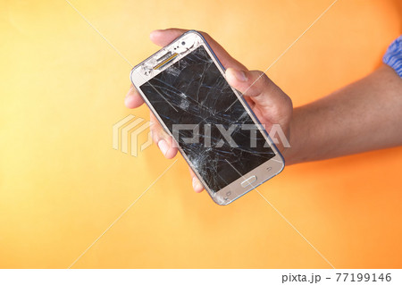 Close up of man hand holding broken smart phone. Close up of man hand holding broken smart phone. 77199146