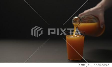 man hand pour mango juice into tumbler glass on black paper background with copy space man hand pour mango juice into tumbler glass on black paper background with copy space 77202892
