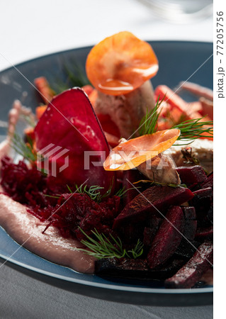 Beet summer salad with arugula, radicchio, soft cheese and walnuts on plate dressing and spices on blue plate, copy space, top view 77205756