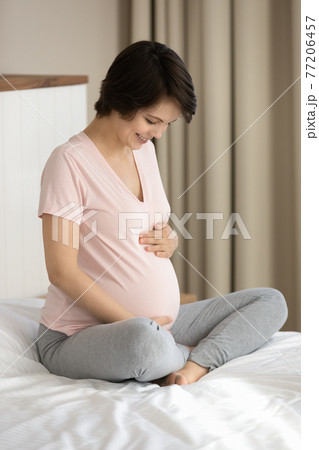 Smiling pregnant woman touch caress baby bump 77206457