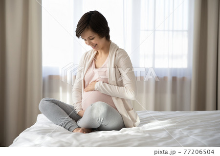 Smiling pregnant woman caress baby bump relaxing 77206504