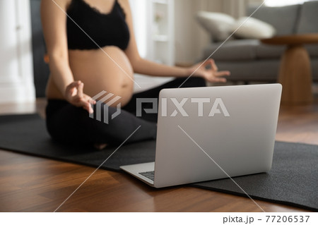 Close up of pregnant woman do yoga class online Close up of pregnant woman do yoga class online 77206537