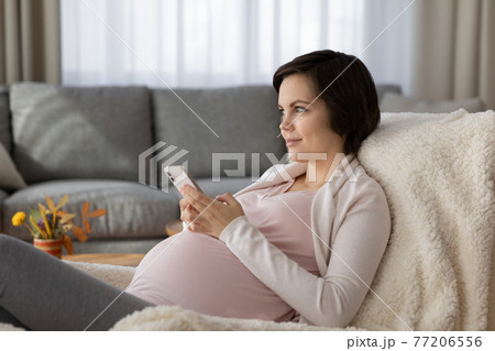 Caucasian pregnant woman use modern smartphone relaxing 77206556