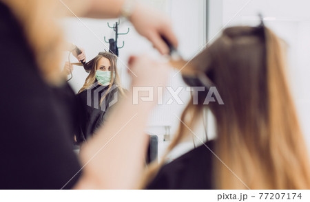 Hair stylist and customer during coronavirus pandemic wearing mask Hair stylist and customer during coronavirus pandemic wearing mask 77207174