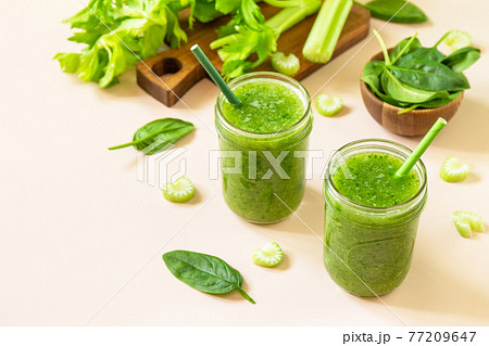 Vegan smoothie recipe. Healthy diet and nutrition, vegan and alkaline drink. Green fresh smoothie with celery and spinach on a pink background. Copy space. Vegan smoothie recipe. Healthy diet and nutrition, vegan and alkaline drink. Green fresh smoothie with celery and spinach on a pink background. Copy space. 77209647