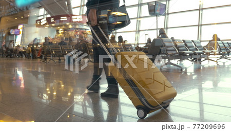 Woman with trolley bag walking slowly in lounge 77209696