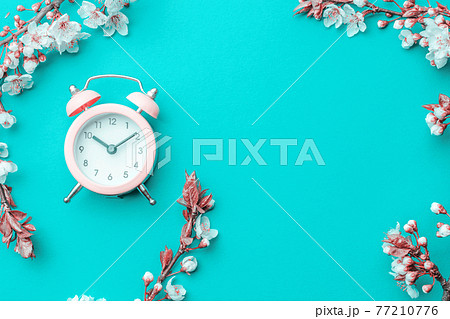 Summer time. Spring blossom and April floral nature with alarm clock on blue background. Beautiful scene with blooming tree. Easter Sunny day. Orchard abstract blurred background. Springtime. 77210776