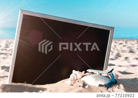 Summer concept background. Starfish, seashells, toy plane and globe near blackboard on ocean nature beach. Copy space for text. 77210922