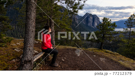 Adventurous Woman Hiking in the mountains during a Spring Sunset Adventurous Woman Hiking in the mountains during a Spring Sunset 77212379