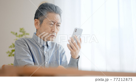 スマートフォンを使う老眼のシニア男性 スマートフォンを使う老眼のシニア男性 77212875
