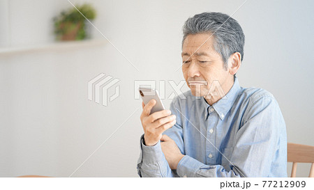スマートフォンの操作に悪戦苦闘するシニア男性 スマートフォンの操作に悪戦苦闘するシニア男性 77212909