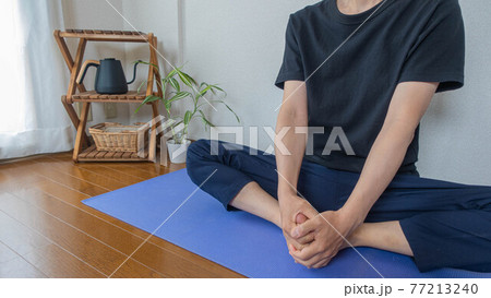 ヨガ 合蹠のポーズ 家でストレッチをする男性 股関節のストレッチの写真素材