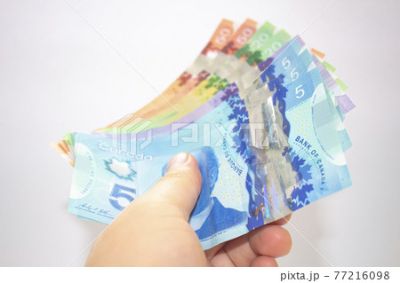 Calgary, Alberta. Canada. April 02, 2021. A person holding canadian bank notes bills. Calgary, Alberta. Canada. April 02, 2021. A person holding canadian bank notes bills. 77216098