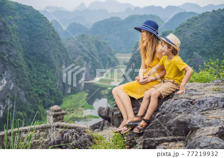 Mother and son tourists on the lake Tam Coc and pagoda of Hang Mua temple, Ninh Binh, Viet nam. It's is UNESCO World Heritage Site, renowned for its boat cave tours. It's Halong Bay on land of Vietnam 77219932