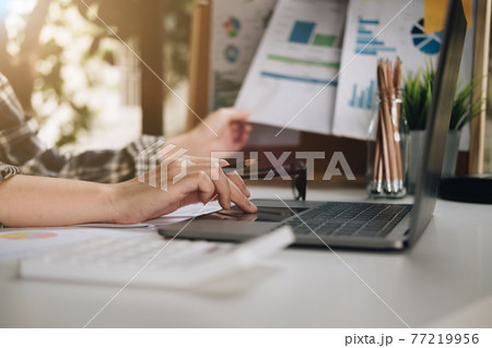 Close up of businessman or accountant hand holding pen working on laptop for business data, accountancy document and laptop computer at office, business concept. 77219956