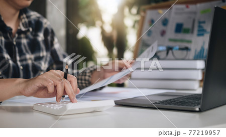 Close up of woman calculate on calculator manage family budget make payment on computer. Female busy take care of household expenses expenditures, paying bills on laptop online. Saving concept Close up of woman calculate on calculator manage family budget make payment on computer. Female busy take care of household expenses expenditures, paying bills on laptop online. Saving concept 77219957