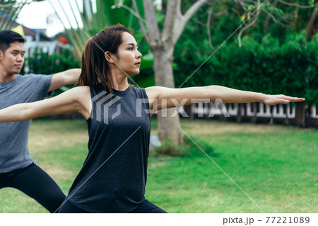 Young Asian couple man and woman practicing yoga in the garden. Summer morning 77221089