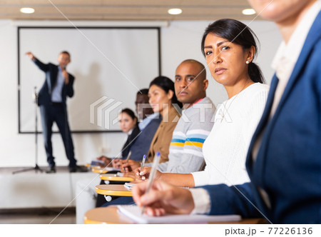 Confident woman listening to lecture at conference Confident woman listening to lecture at conference 77226136