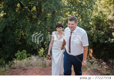 Newlyweds hold hands on the background of the forest 77227558