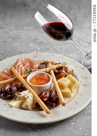 Set of snacks for wine. Prosciutto, parmesan, gorgonzola, almonds, olives, bread chips, mostard fruit confiture on gray marble background 77228968