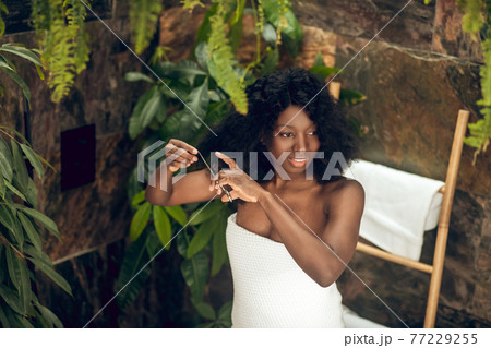 Beautiful african american woman cutting her hair ends Beautiful african american woman cutting her hair ends 77229255