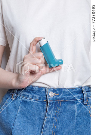Woman holds inhaler to treat asthma. World Asthma Day. Concept of allergy care 77230495
