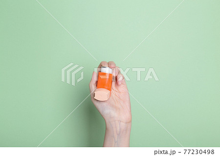 Hand holds inhaler to treat asthma. World Asthma Day. Concept of allergy care Hand holds inhaler to treat asthma. World Asthma Day. Concept of allergy care 77230498