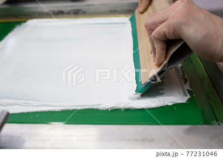 Serigraphy silk screen print process at clothes factory. Frame, squeegee and plastisol color paints Serigraphy silk screen print process at clothes factory. Frame, squeegee and plastisol color paints 77231046