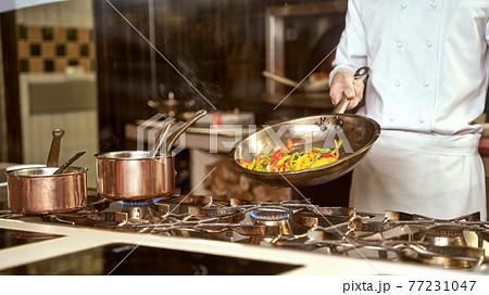 Restaurant chef cooking pepper slices on a pan Restaurant chef cooking pepper slices on a pan 77231047