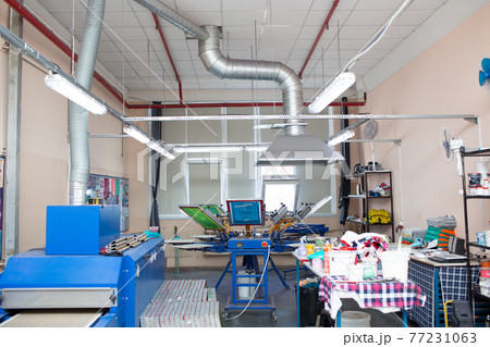 Serigraphy silk screen print process at clothes factory. Frame, squeegee and plastisol color paints Serigraphy silk screen print process at clothes factory. Frame, squeegee and plastisol color paints 77231063