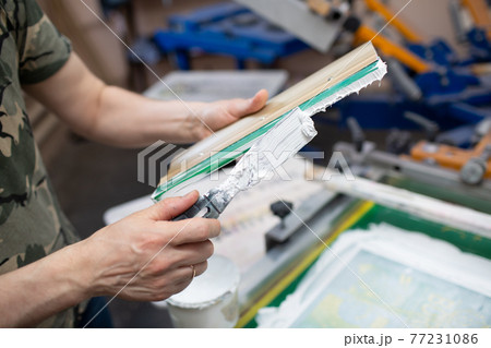 Serigraphy silk screen print process at clothes factory. Cleansing Frame, squeegee and plastisol color paints 77231086