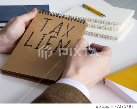 Businessman thinks about tax lien and holds notepad. 77231487
