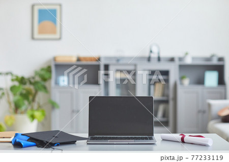 Laptop on desk with graduation hat 77233119