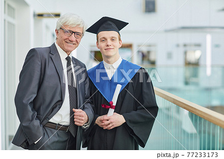 Young man posing with professor at graduation ceremony Young man posing with professor at graduation ceremony 77233173
