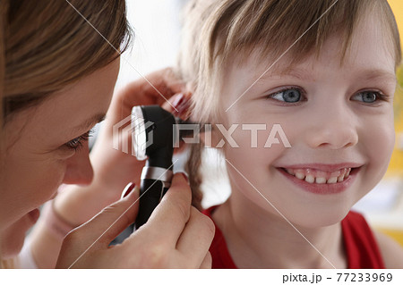 Ent doctor examining sore ear of small child using otoscope Ent doctor examining sore ear of small child using otoscope 77233969