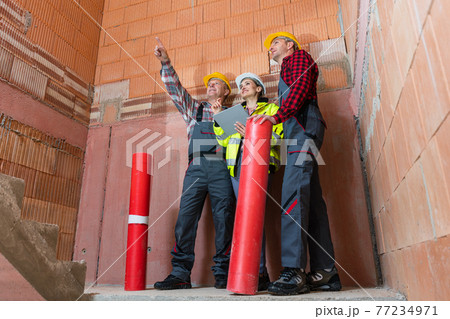 Male construction workers discussing project of building Male construction workers discussing project of building 77234971