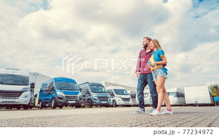 Woman and man choosing camper van to rent or buy 77234972