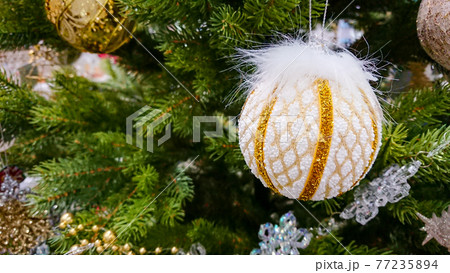 White and golden Christmas ball ornaments against the backdrop of a Christmas tree White and golden Christmas ball ornaments against the backdrop of a Christmas tree 77235894