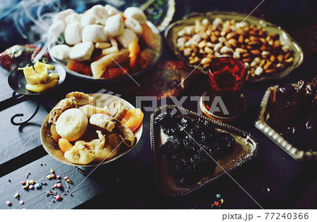 Eastern sweets. Dried fruits. Nuts. Haze from an extinguished candle. Eastern sweets. Dried fruits. Nuts. Haze from an extinguished candle. 77240366