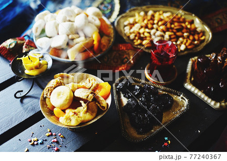 Eastern sweets. Dried fruits. Nuts. Haze from an extinguished candle. Eastern sweets. Dried fruits. Nuts. Haze from an extinguished candle. 77240367