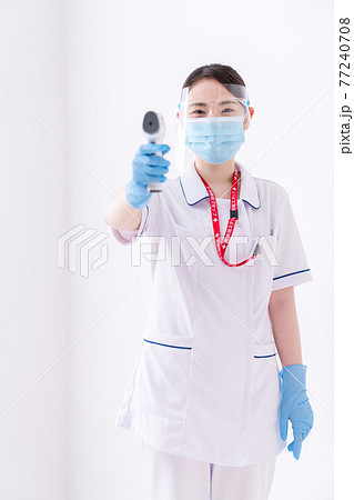 非接触体温計で体温測定をする看護師 非接触体温計で体温測定をする看護師 77240708