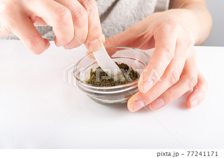 Mix cosmetics in a glass container. Green powder in a glass dish. 77241171