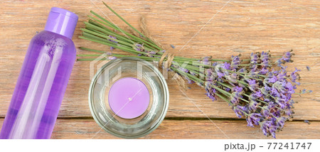 lavender flowers, scented candle and lavender shampoo on a wooden table. Wide photo. 77241747